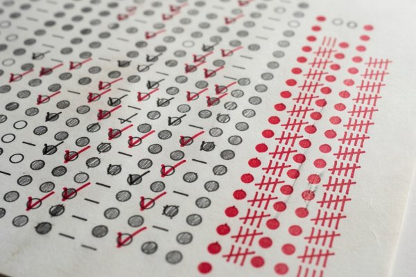 Close-up of scorekeeper desk with red pens, running tally sheet, and calculator